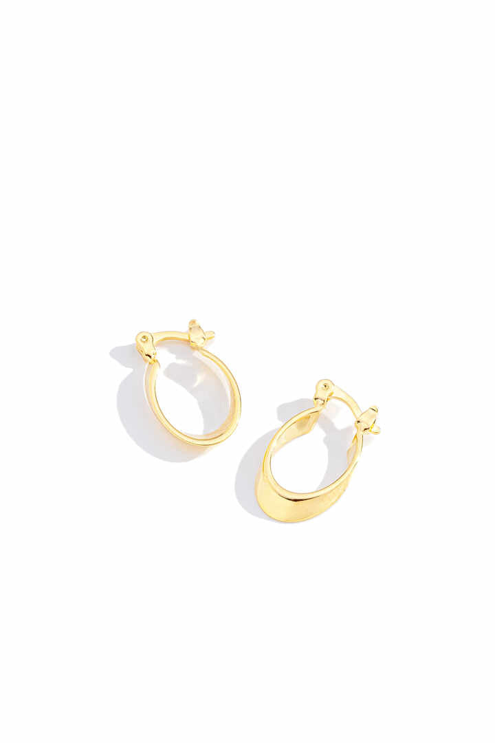 Brinco - Argola Elíptica Argola com formato elíptico inclinado, medindo 17x11 mm, com design geometrico moderno e acabamento polido em dourado.Uma peca difere