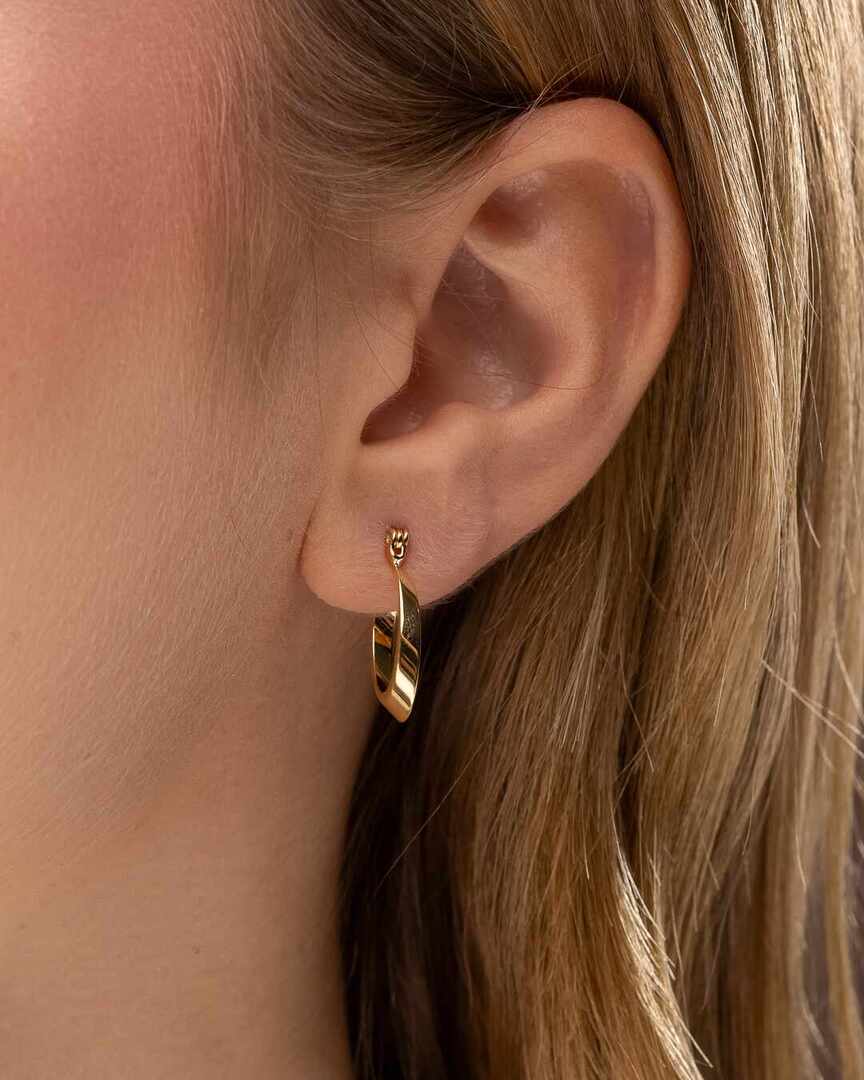 Brinco - Argola Elíptica Argola com formato elíptico inclinado, medindo 17x11 mm, com design geometrico moderno e acabamento polido em dourado.Uma peca difere